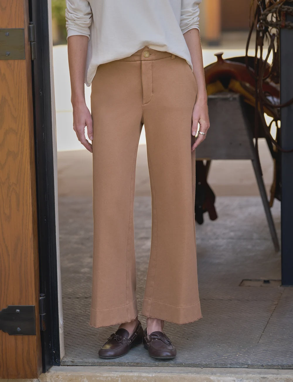Frank &amp; Eileen Riley wide leg trousers styled with a white top and brown loafers in a doorway setting.