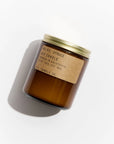 A brown glass jar candle with a gold metal lid and kraft label reading “PFC Candle” by Faire sits on a white background—one of their hand-poured candles, crafted with fine fragrance oils for an inviting aroma.