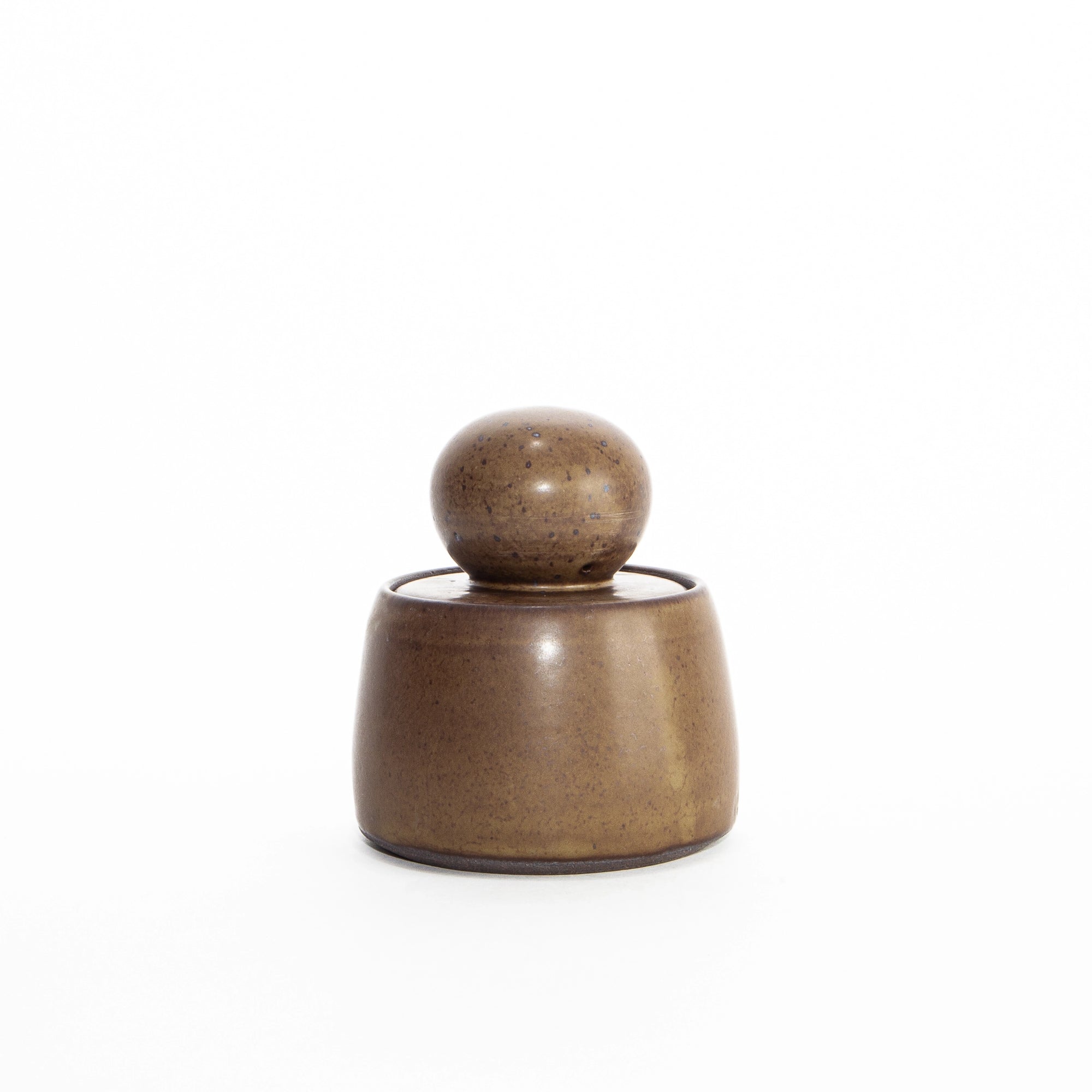 The Faire Olive Brown Stash Jar is a small, hand-thrown stoneware jar with a rounded lid and smooth satin glaze, shown against a plain white background.