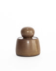 The Faire Olive Brown Stash Jar is a small, hand-thrown stoneware jar with a rounded lid and smooth satin glaze, shown against a plain white background.