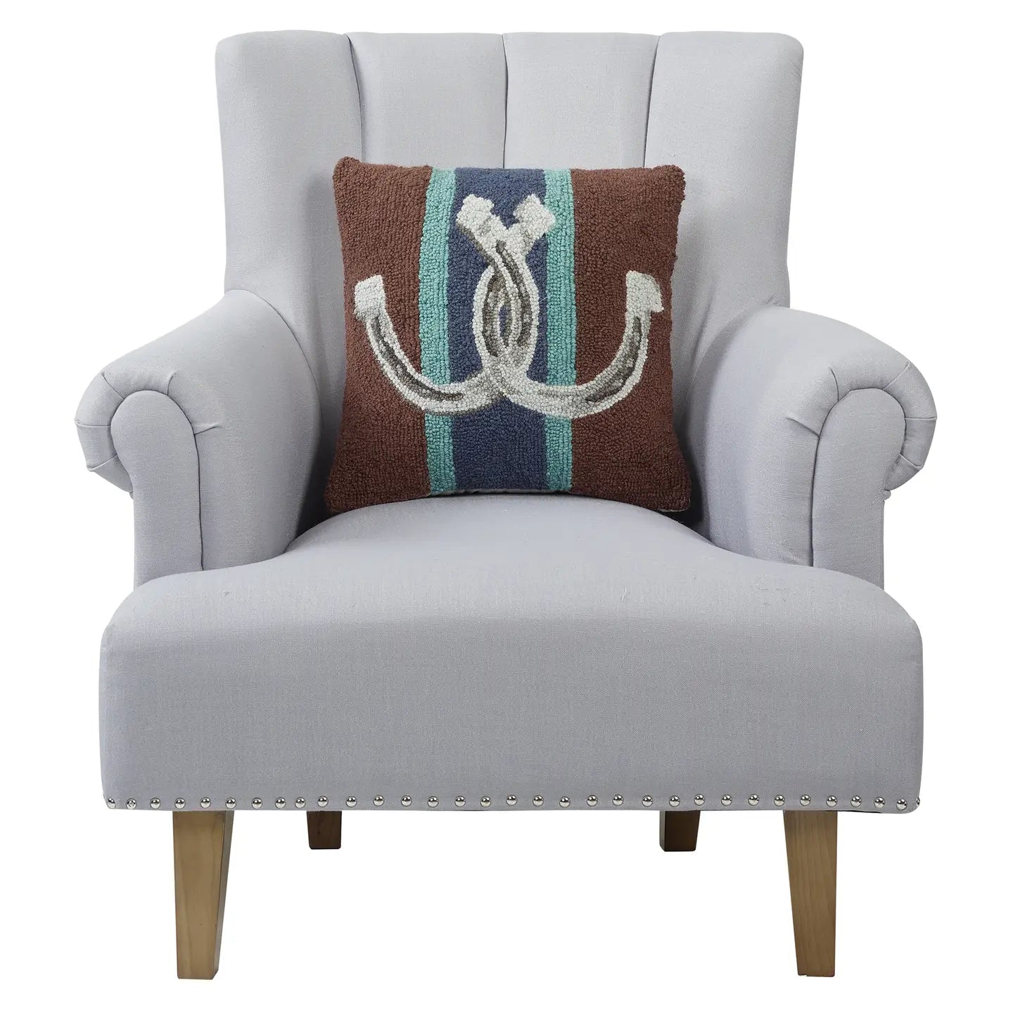 A light gray upholstered armchair with wooden legs and silver studs at the base, featuring Faire's Country Club Pillow—a brown polyester velvet throw pillow with a blue vertical stripe and white horseshoe design.