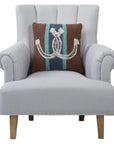 A light gray upholstered armchair with wooden legs and silver studs at the base, featuring Faire's Country Club Pillow—a brown polyester velvet throw pillow with a blue vertical stripe and white horseshoe design.