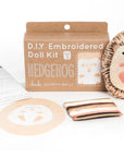 The Faire Hedgehog Embroidery Kit includes a hedgehog pattern, finished doll, instructions, fabric pieces, colorful thread, and a Level 3 "Hedgehog" box—perfect for anyone who loves making embroidered dolls.