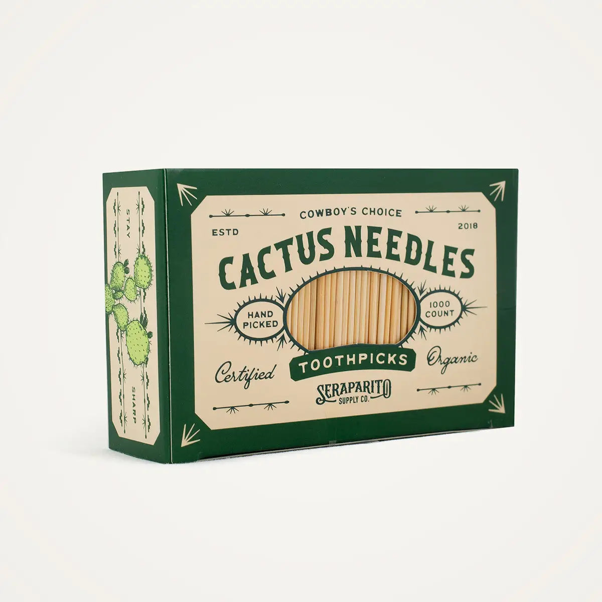 A green and beige box of Faire's "Cactus Needle Toothpicks," showcasing a vintage design with a small cactus illustration, labeled "Cowboy's Choice" and "Certified Organic," contains 1000 hand-picked toothpicks.