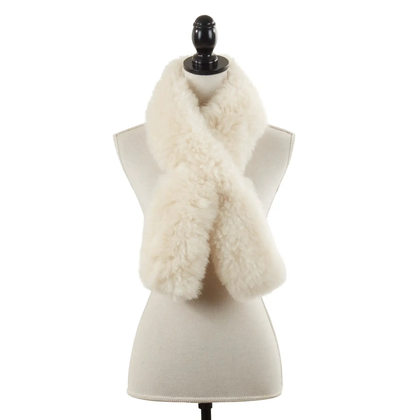 The Faire Lamb Fur Pull Through, a cream-colored, fluffy scarf, is styled in a crisscross on a beige dress form with black stand and finial, radiating luxurious warmth.