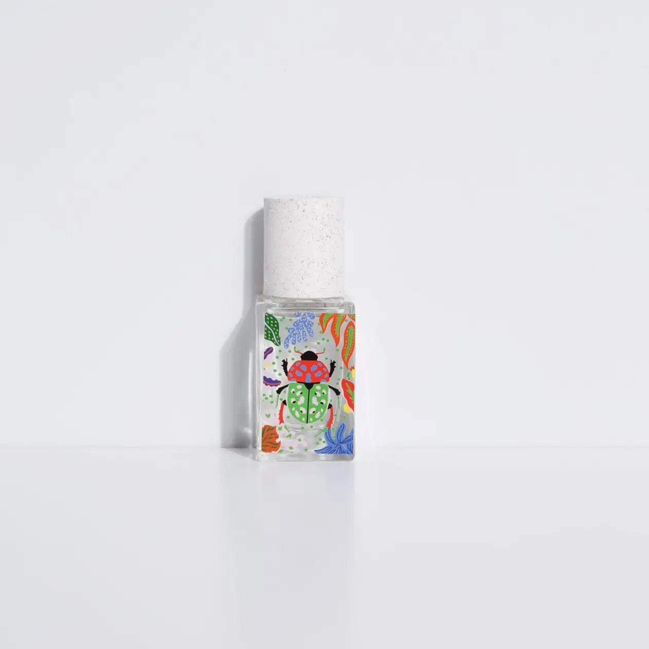 The Maison Matine Perfume by Faire features a clear glass bottle with a white cap, adorned with vibrant floral and leaf designs, standing upright against a plain white background, and evokes notes of vanilla and bergamot.