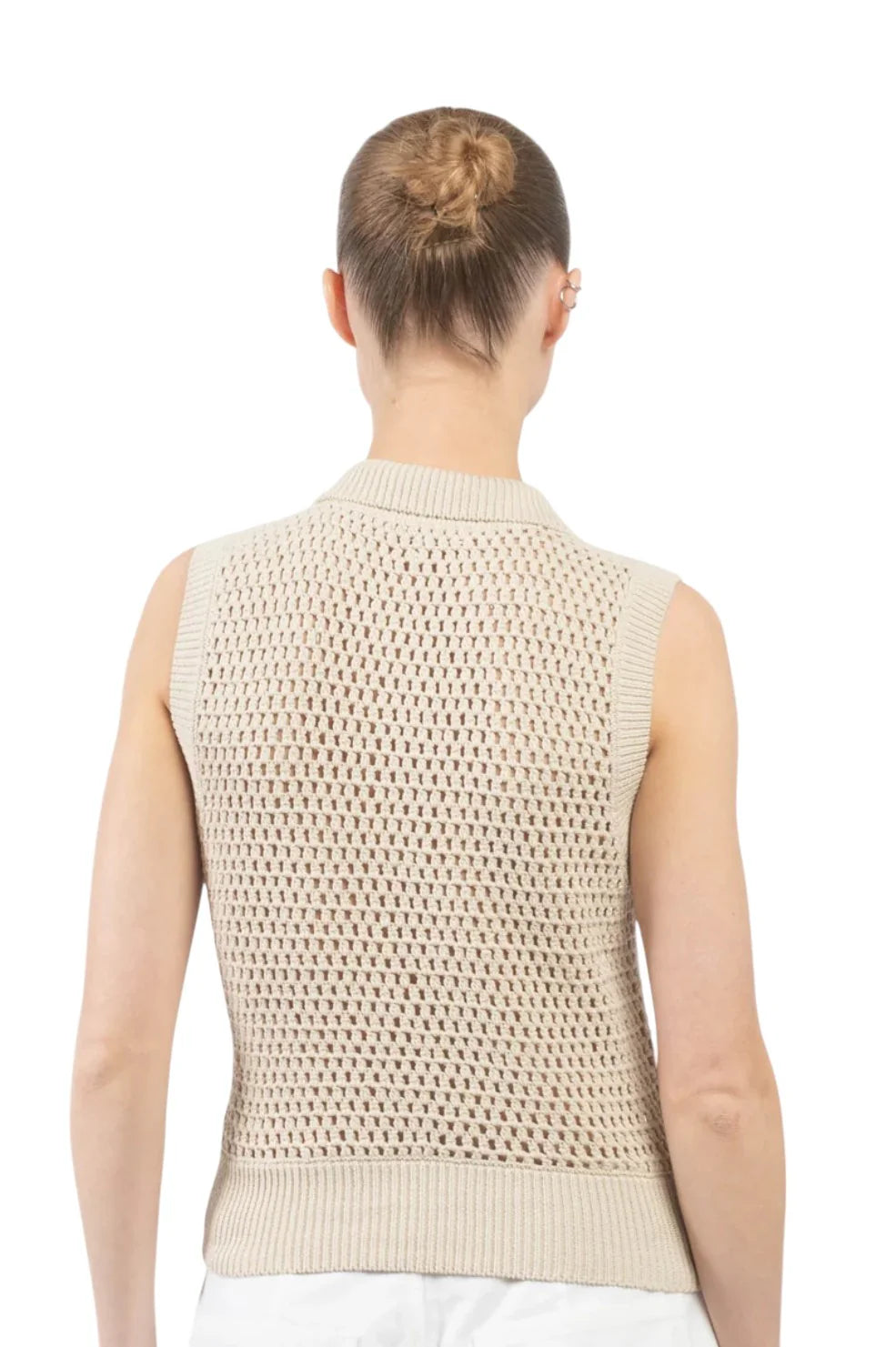 A person with light skin and brown hair in a bun is seen from the back, wearing FRAME's The Polo Vest—a sleeveless, beige open-knit sweater vest with subtle cable stitching—set against a white background.
