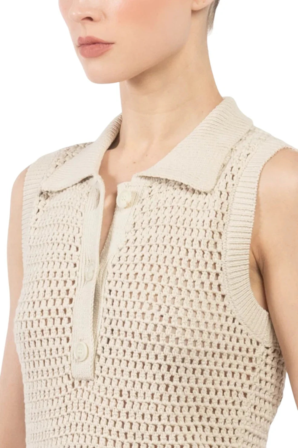 A person wears The Polo Vest by FRAME—a sleeveless beige crochet top with a collared, button front and cable stitchwork—shown from the shoulders up against a plain background.
