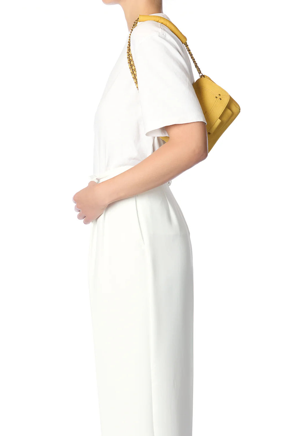 Against a white background, a person in a white outfit is holding the Lulu Small Bag by Jerome Dreyfuss, a yellow mini messenger bag with a leather strap over their shoulder.