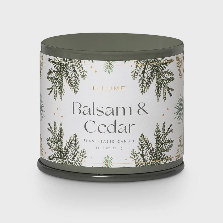 A sophisticated green jar candle from Creative Co-op, the Illume Balsam & Cedar Plant-Based Candle, features elegant illustrations of pine branches with gold accents. Weighing 11.8 oz (335 g), it embodies an aesthetic similar to that of a Vanity Tin Candle.