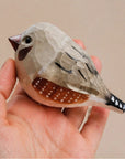 Gray hand-painted carved wood bird figurine by Faire, crafted from basswood, shown in hand for scale.