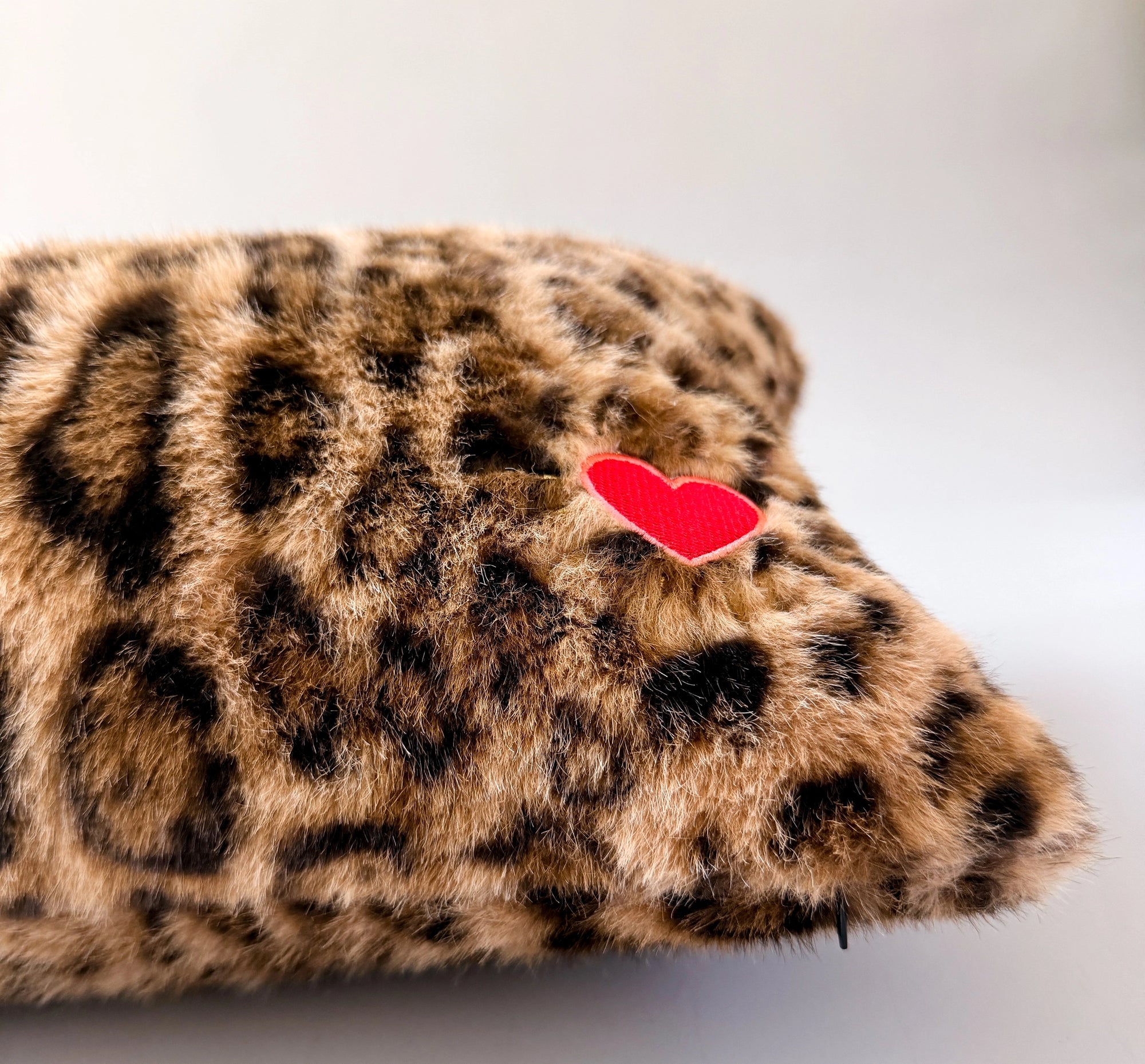 Leopard print lumbar pillow with red heart patch in faux fur by Faire, ideal for accenting sofas or beds.