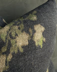 The Faire French Linen Roses Pillow features a dark gray, stone-washed texture with a faded beige and green floral design, shown against a plain gray background.