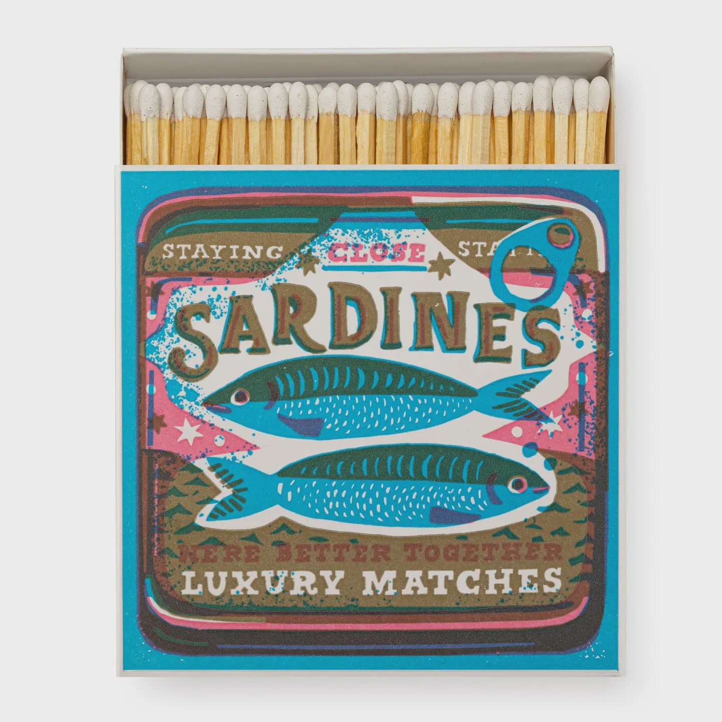 The Square Matches by Faire feature a retro sardine can design with illustrated sardines and text reading "Staying Close," "Sardines," and "We're Better Together." These nostalgic matchboxes add a fun touch to any space.