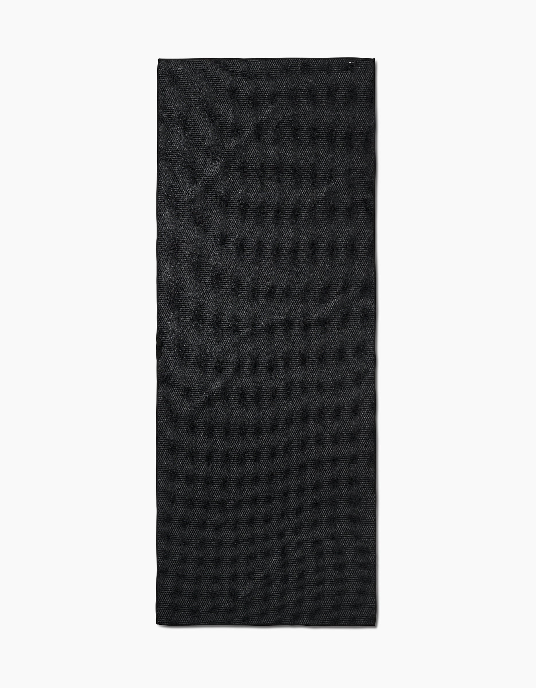 The Faire Chic Checker Yoga Towel, a rectangular, ultra-absorbent black towel with a plain design and subtle creases, is laid flat on a white background.