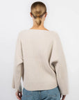 A person with light brown hair in a low bun wears the Rag & Bone ingrid boat neck sweater in cream and blue jeans, facing away from the camera against a plain white background.