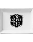 The Faire Ceramic Tray is a rectangular white ceramic piece with a black vintage-style "Paris Ritz Hotel" emblem and floral accents—ideal as a jewelry organizer or trinket tray gift.