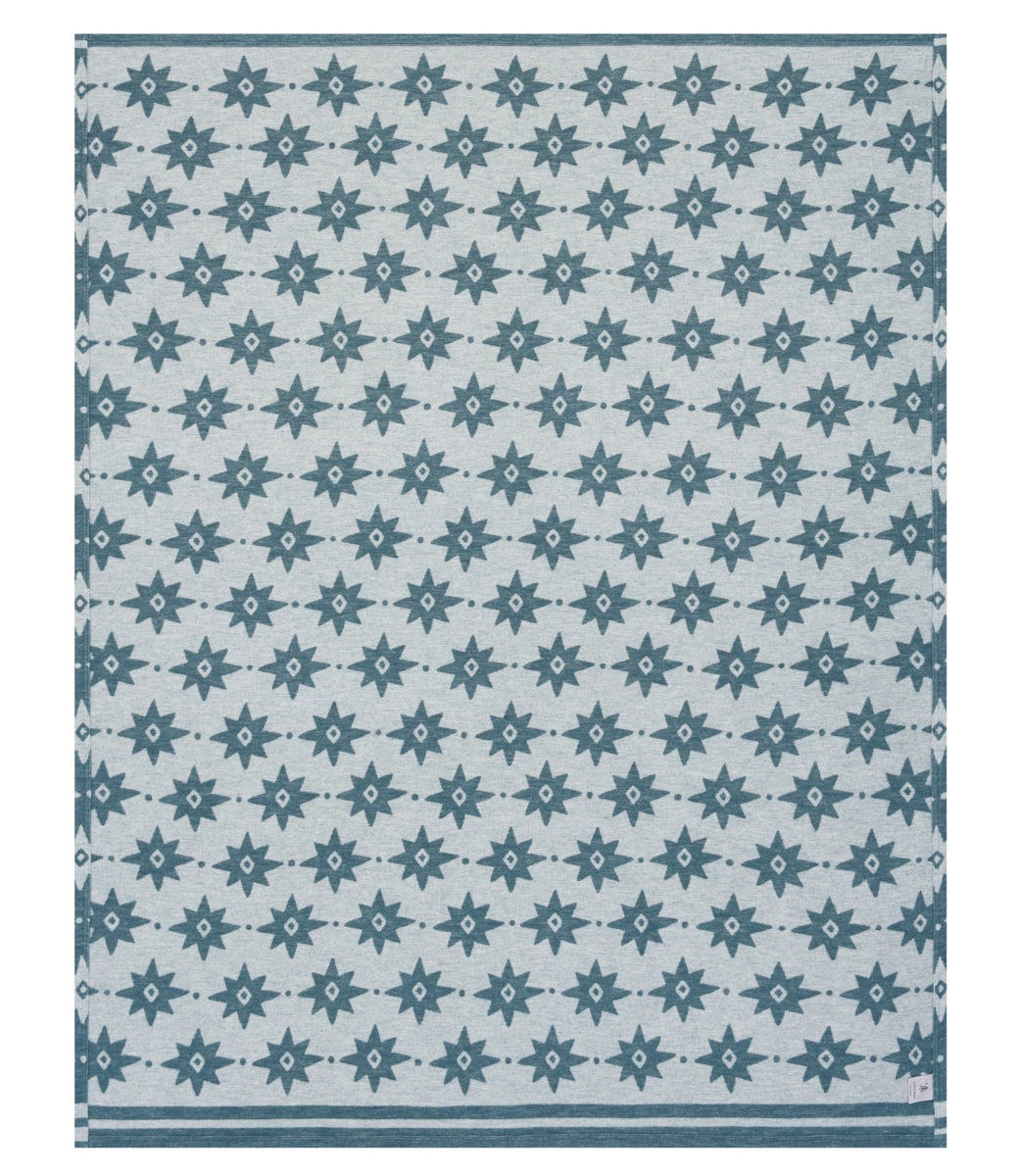 The Faire Big Sky Lightweight Blanket is made from Chappy material, with a light gray base, repeating blue six-pointed stars, and two horizontal blue stripes along the bottom.