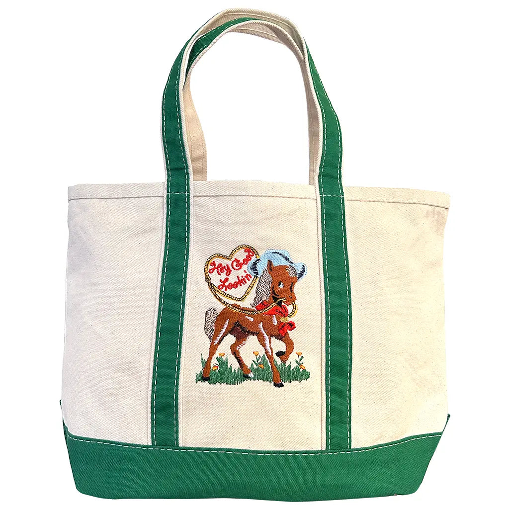 The Faire "Hey Good Lookin'" bag is a cream and green embroidered tote featuring a pony with a blue mane and a heart sign—perfect for daily essentials or as a cute makeup bag.