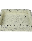 The HomArt Terrazzo Tray White features a speckled pattern with black, gray, and dark green fragments on light beige, resembling elegant marble. Its raised edges and smooth surface make it ideal for holding small items.