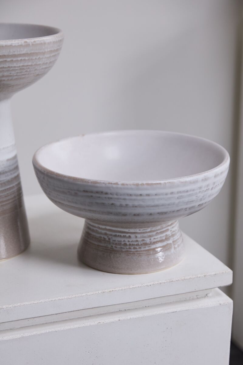 The Lorca Footed Bowl by Accent Decor features a sturdy base and wide, shallow shape with a white-to-light gray gradient, making it ideal for home decor or stylish bowl fillers. It sits elegantly on a white surface beside a similar vessel.