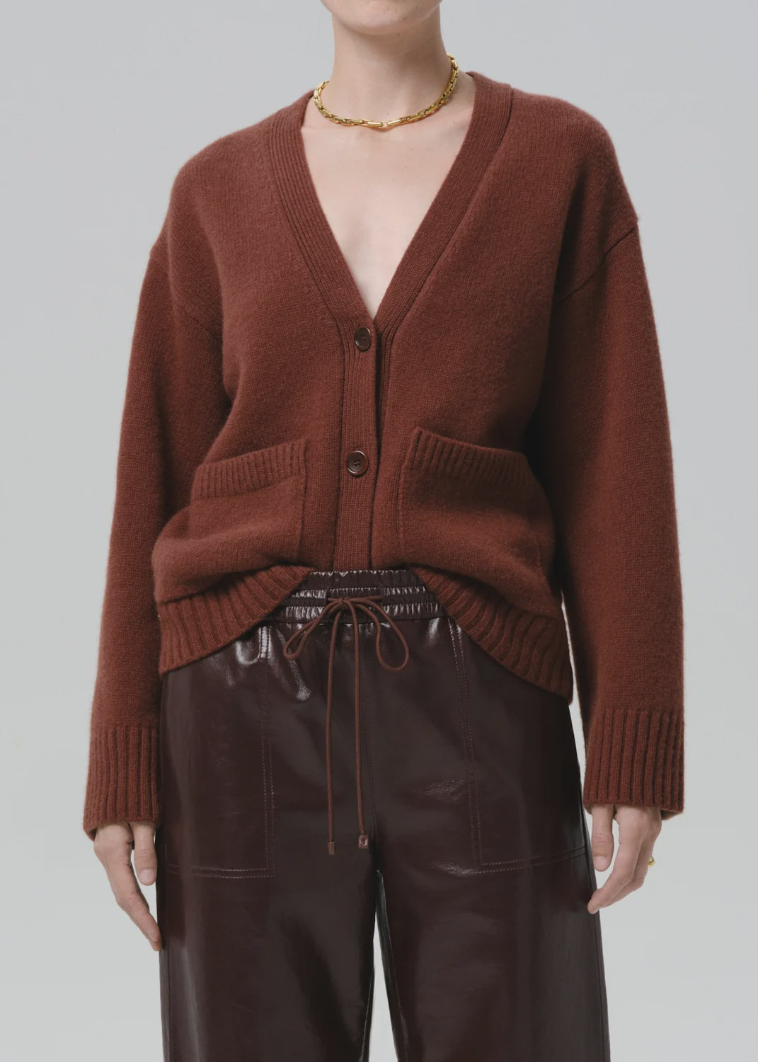 Woman modeling a slouchy cardigan sweater by Citizens of Humanity, styled with leather pants and gold necklace.