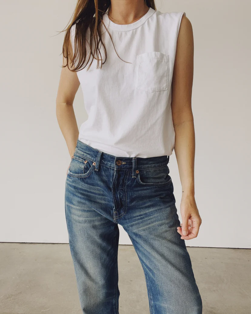 A person wearing "The Muscle Tee" by Hey Gang, paired with blue jeans, stands against a plain white background with one hand in their pocket.