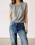 A person wearing "The Muscle Tee" by Hey Gang and blue jeans stands against a plain white background. The casual outfit is simple and relaxed, exuding an effortless vibe.