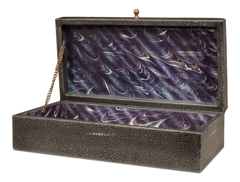The Gatsburg Shagreen Box by Sarreid is rectangular, tawny brown, with a hinged lid topped by a gold knob. Inside, it has a purple marbled lining and a small gold chain securing the open lid.