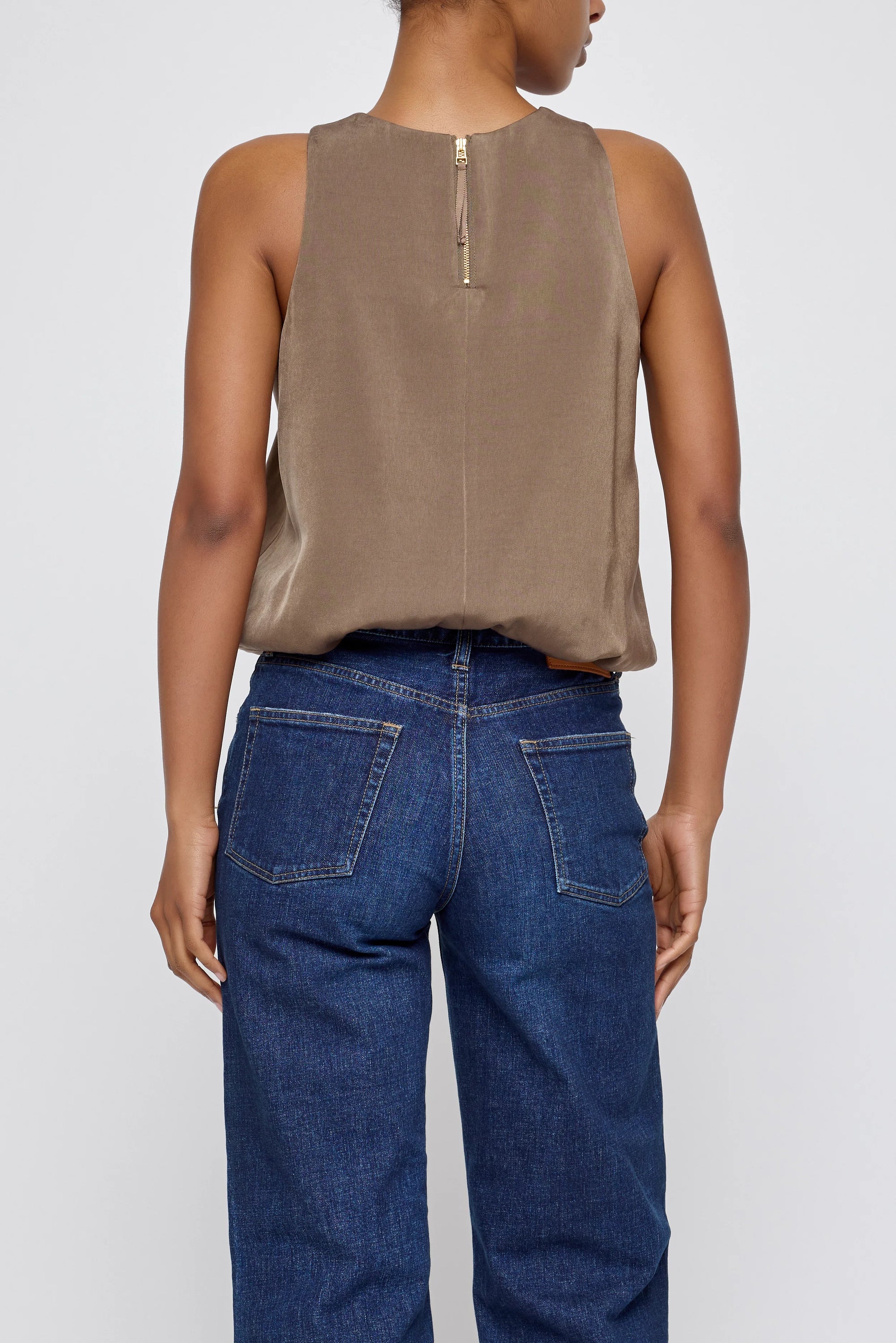 Brown sculpted satin sleeveless top by Moussy with back zipper, shown from behind, paired with blue jeans.