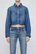 A person wears the Moussy Foley Shirt, a women's cotton denim cropped button-down jacket with long sleeves and a collar, paired with high-waisted blue jeans, standing against a plain light background.