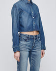 A person wears the Moussy Foley Shirt, a cropped denim button-down with long sleeves, paired with matching blue denim jeans against a plain light background.
