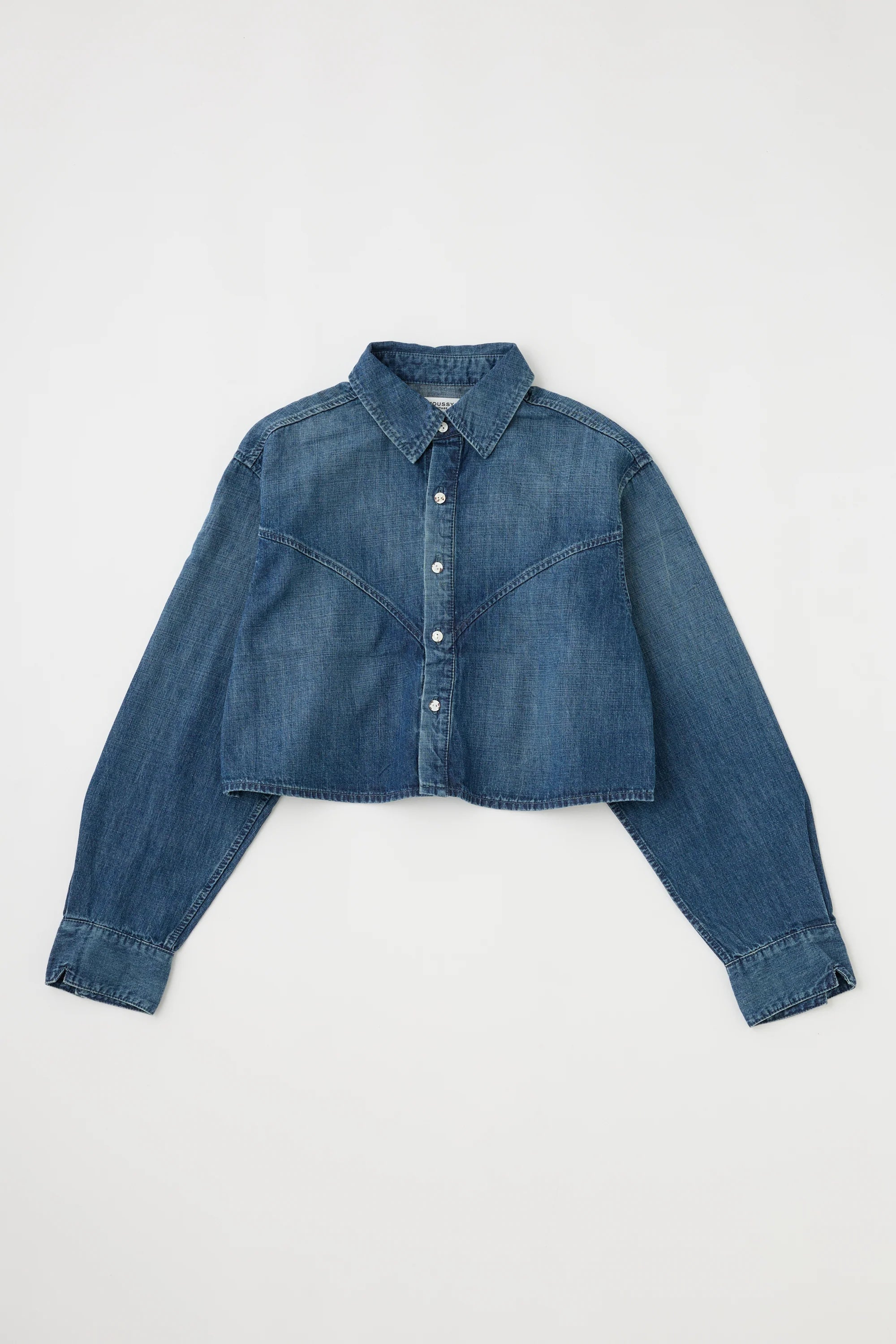 The Foley Shirt by Moussy is a women's cropped denim button-down with long sleeves, pointed collar, and visible seams, shown laid flat on a white background.