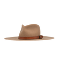 The Stratford Fedora by Ninakuru is a wide-brimmed hat crafted from light brown felt wool, accentuated with a darker brown leather band and buckle around the base. It offers both stylish charm and sun protection while being ethically made to ensure quality and sustainability, making it the perfect blend of fashion and conscience.