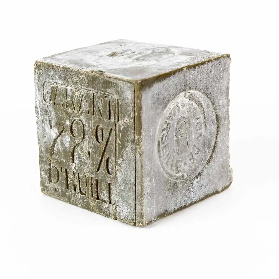 Marseille Olive Oil Soap by Cie Luxe Brands is a gray cube embossed with "GARANTI 72% D'HUILE" and a circular French stamp, showcasing its authentic use of rich botanical oils and rustic, traditional French craftsmanship.