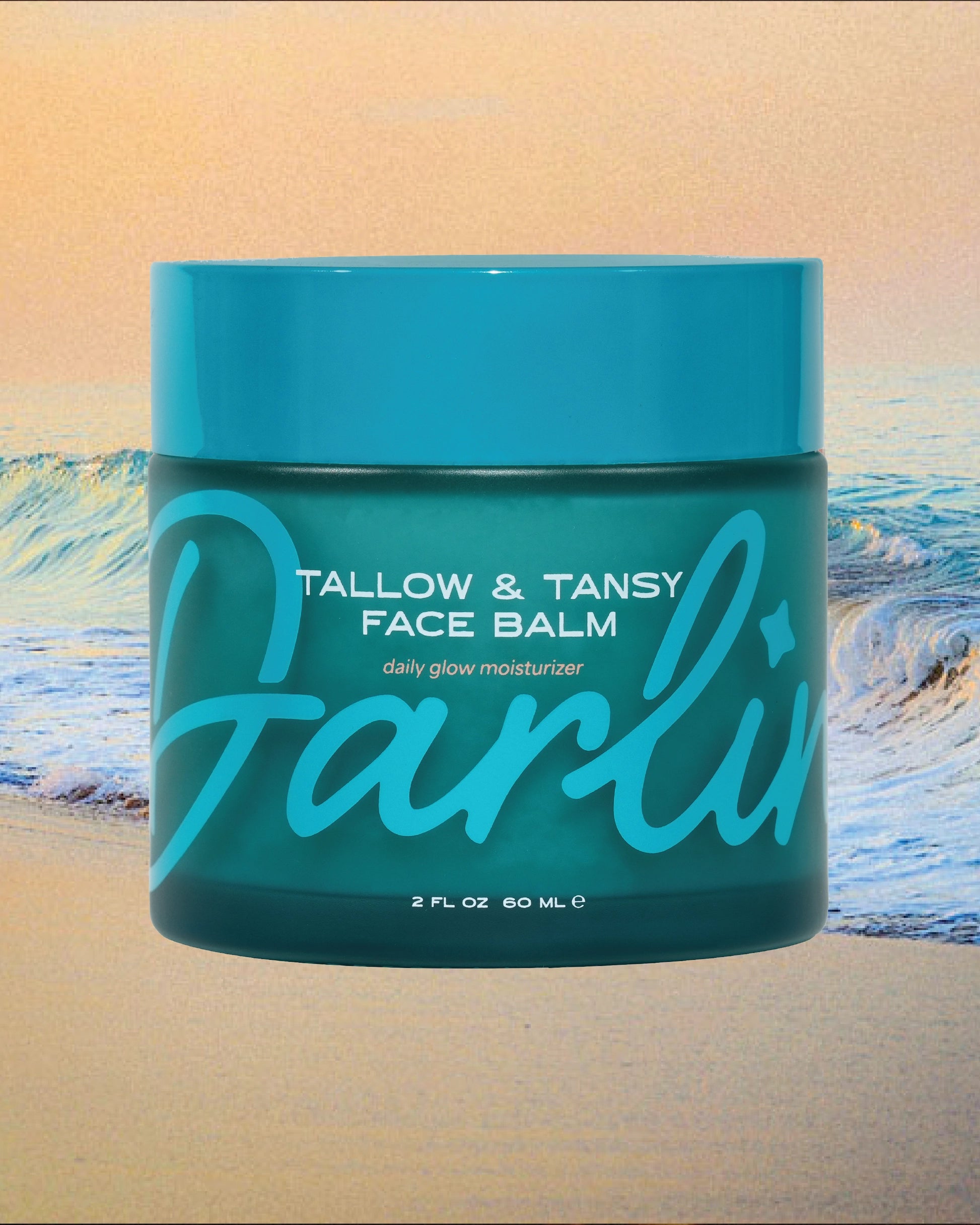 A teal jar of Faire's Tallow Face Balm Moisturizer sits before ocean waves. Made with grass-fed tallow for daily glow, "Darlin" is written in bold script across the jar.