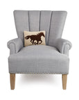 Gray armchair with wood legs, styled with Faire’s wool hooked Racehorse Silhouette Pillow.