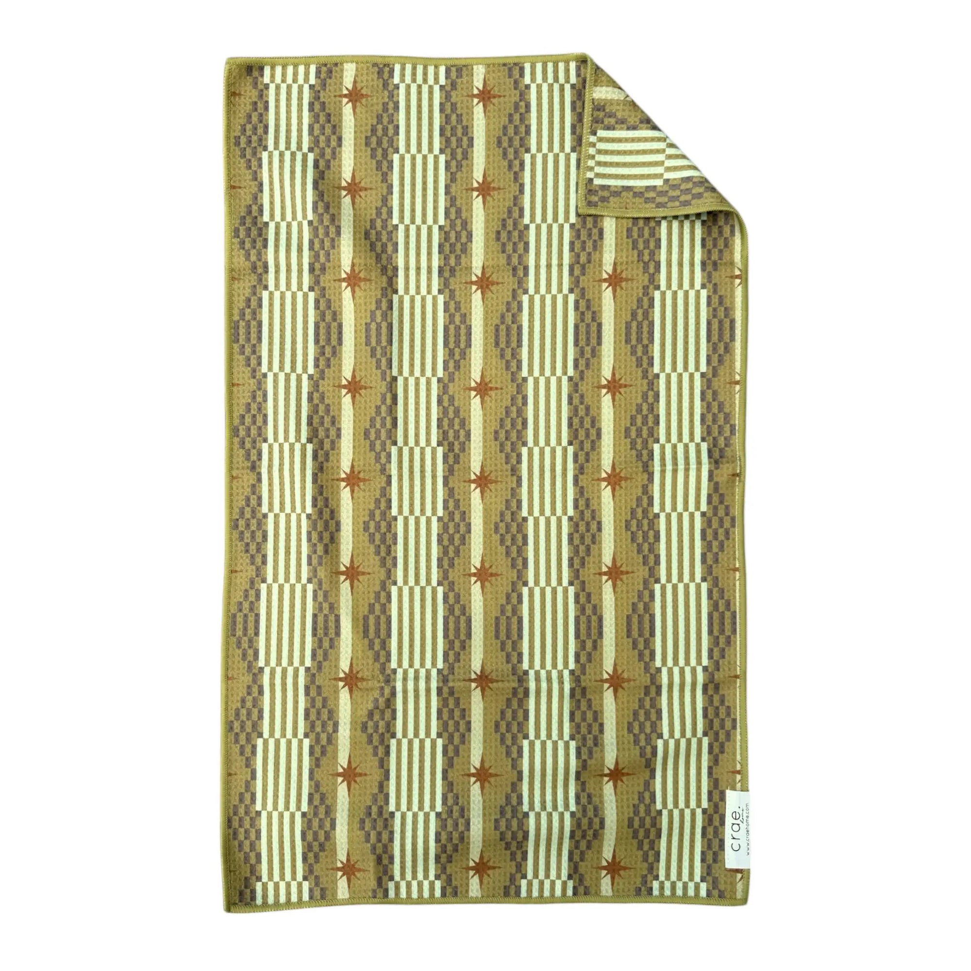 The Faire Double Sided Hand Towel features a high-absorbent waffle weave microfiber with geometric patterns in beige, brown, and olive green. Vertical stripes and starbursts add style, while a folded corner shows the reverse. Eco-friendly design.