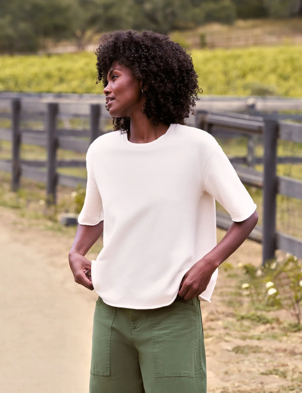 Green pants styled with a Frank &amp; Eileen Perry NYC Crew Tee, worn casually outdoors by a wooden fence.
