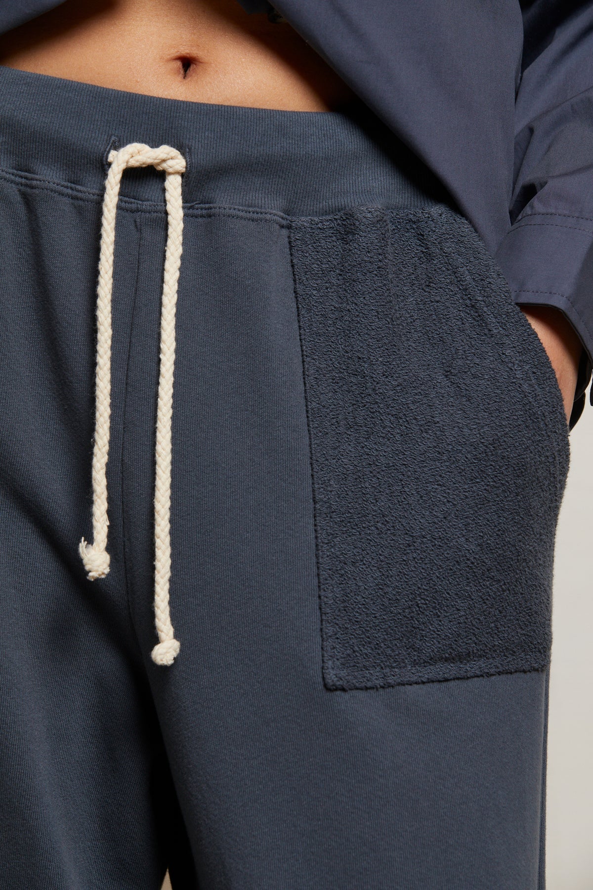 A close-up of a person wearing the Perfectwhitetee French Terry Pant—navy blue, 100% cotton, straight-leg lounge pants with a textured patch pocket and white drawstring—paired with a matching navy top.