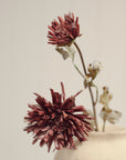 Burgundy Dahlia Spray faux flowers in a decorative vase by Faire, shown against a plain background.