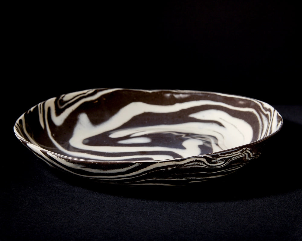 The Faire Porcelain Serving Bowl - Black & White 10" boasts a handcrafted marbled design with swirling black and white patterns, perfect for stylish serving.