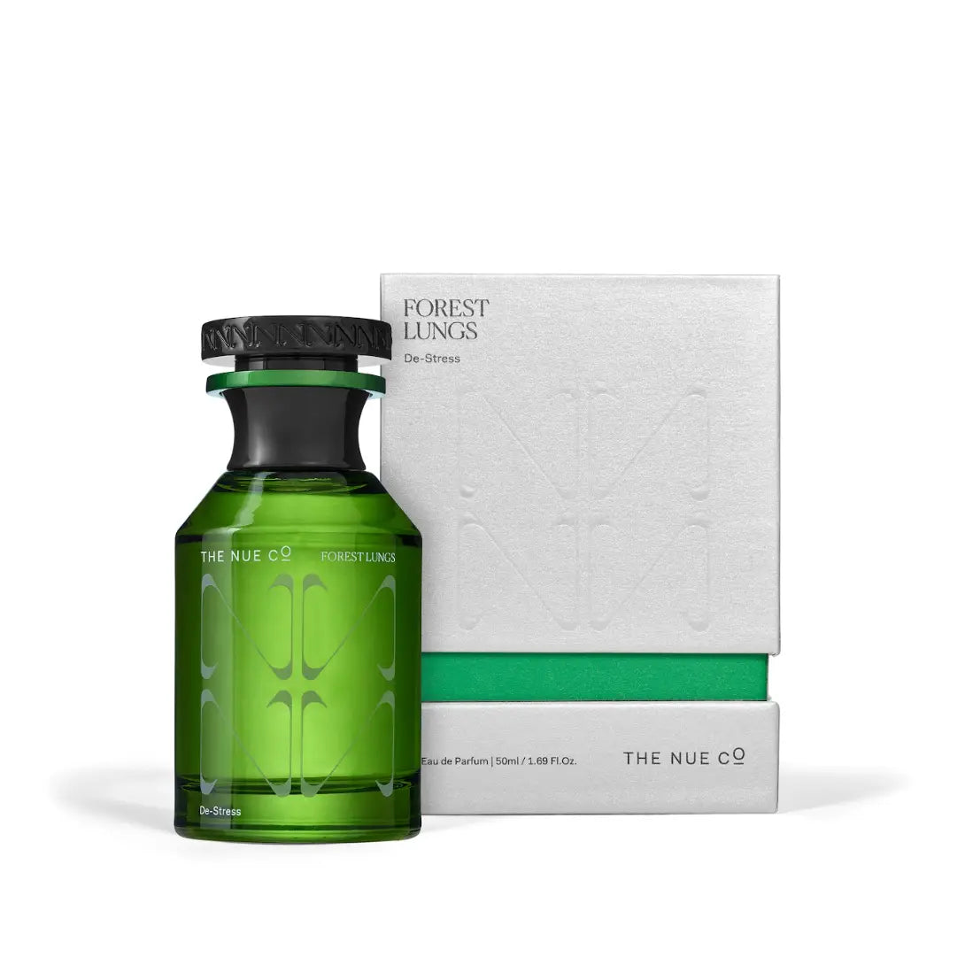 A green glass bottle of The Nue Co Forest Lungs 50ML anti-stress fragrance is displayed beside its matching white and green box, both showcasing a minimalist, modern design for natural stress relief.