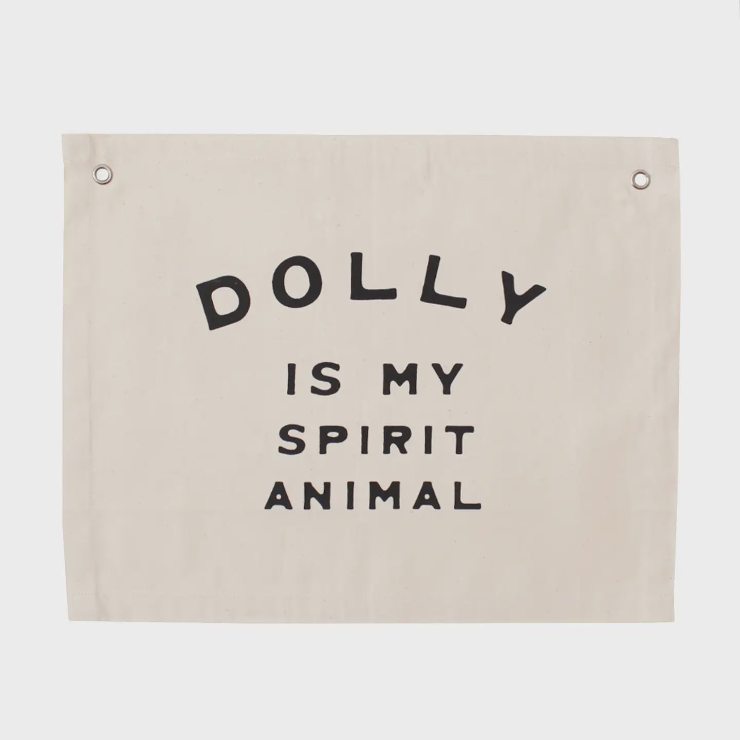 A beige Canvas Banner from Faire boldly displays the phrase "DOLLY IS MY SPIRIT ANIMAL" in striking black letters. It features two metal grommets at the top corners for easy hanging.