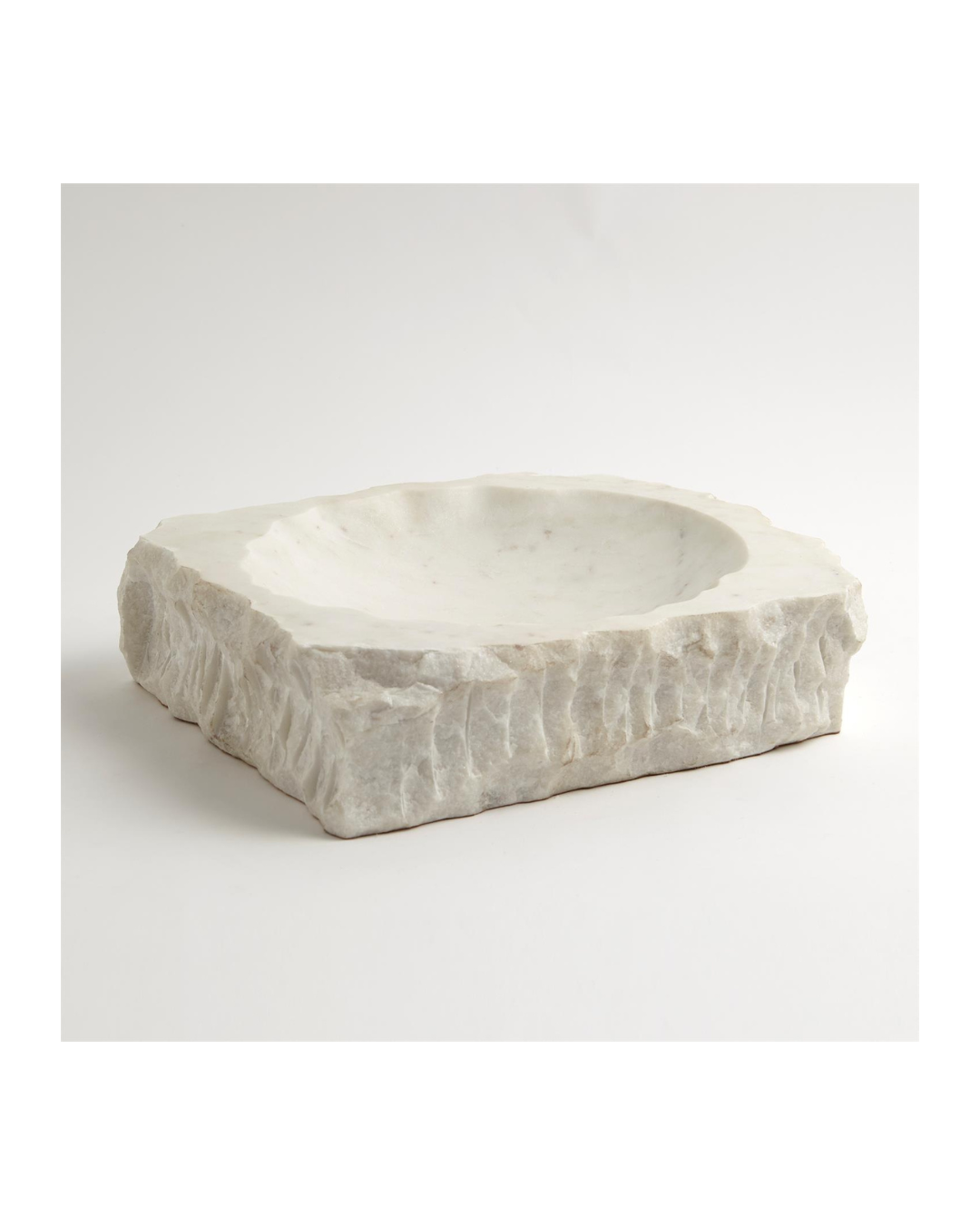 The Chiseled Block Bowl by Global Views is a square white marble basin with rough edges and a smooth interior, exuding natural rustic charm against a plain white background.
