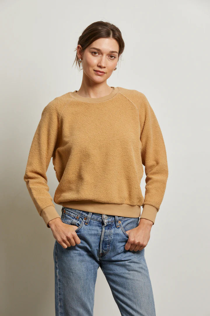 A person wearing the Perfectwhitetee Ziggy Reverse LS Sweatshirt and blue jeans stands against a plain light background, hands in pockets, gazing confidently at the camera.