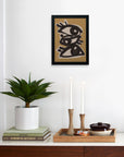 A modern, minimalist room displays a potted plant, books, and a tray with candles and a teapot. Above, Faire’s Abstract line art eyes—limited edition art on matte paper—depicts three outlined eyes on a tan background.