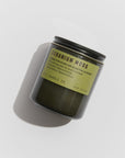 A dark green candle jar with a black lid labeled in bold, "Geranium Moss - 7.2 oz Alchemy Soy Candle" by Faire. Crafted from soy wax, it features scent notes and details on the label. Resting on a light surface casting a shadow, this candle captures sustainable patchouli elegance.