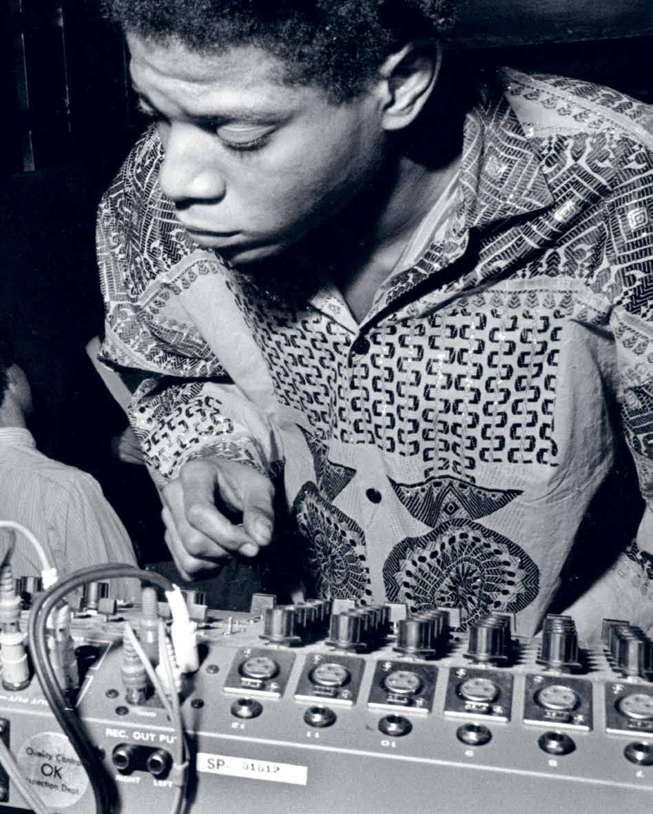 In a black and white photo echoing Basquiat’s creative energy, a young man in a patterned shirt adjusts sound mixer controls—a scene inspired by "Seeing Loud, Basquiat and Music" from Simon & Schuster Inc.