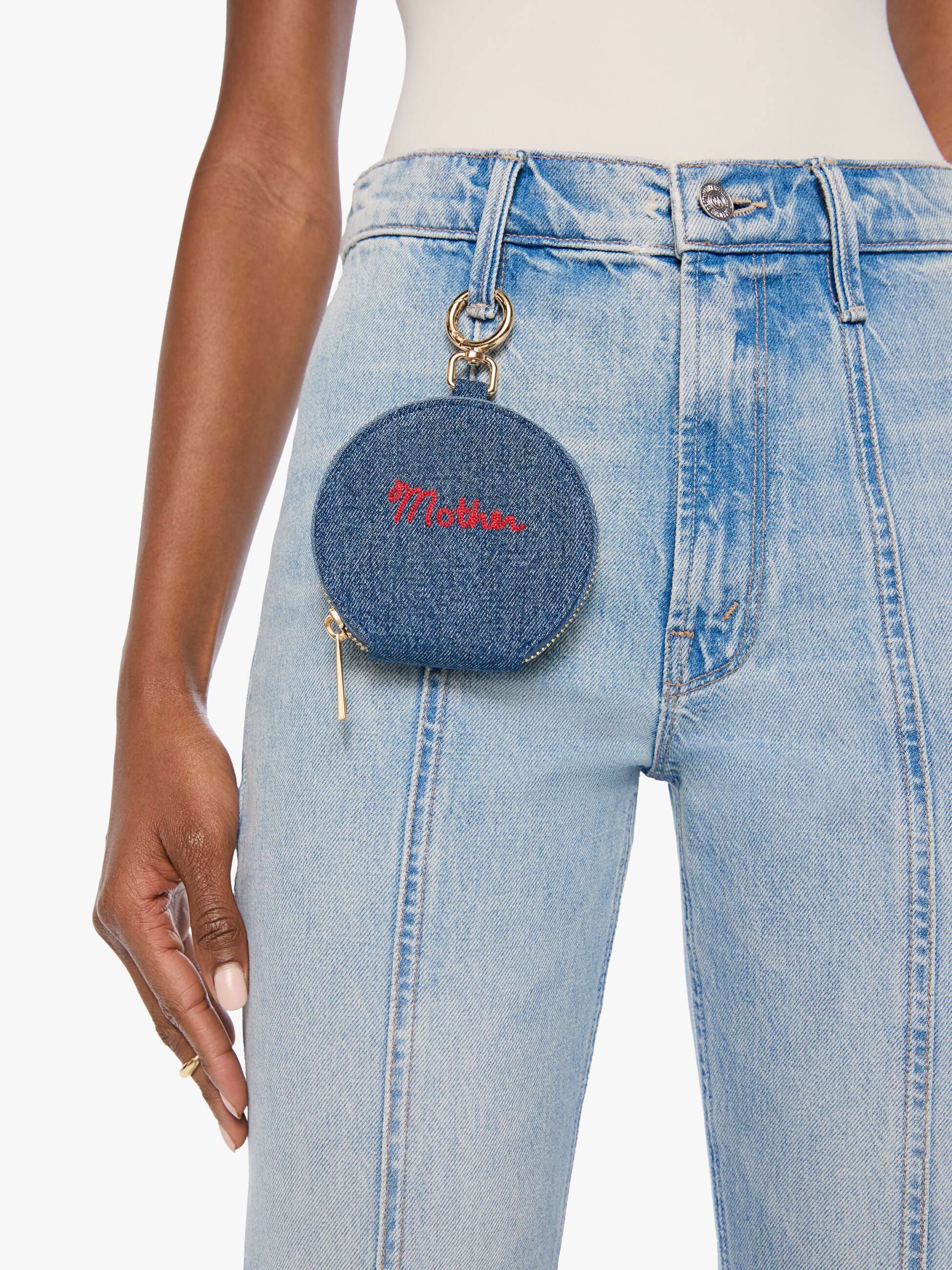 Round blue denim coin purse with red Merci embroidery by Mother, attached to light wash jeans key ring.